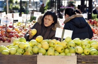 A woman picks through apples at an outdoor market in New York.