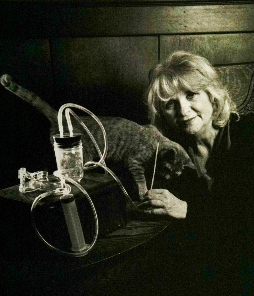 Carol Downer holding a Del-Em Kit, with her cat, Red