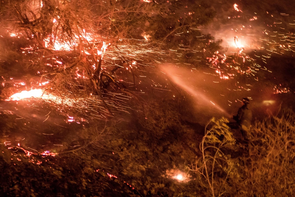 TOPSHOT-US-CALIFORNIA-WILDFIRES A man firefighter works to extinguish the Creek Fire as it burns along a hillside near homes and horses in the Shadow Hills neighborhood of Los Angeles, California, on December 5, 2017.