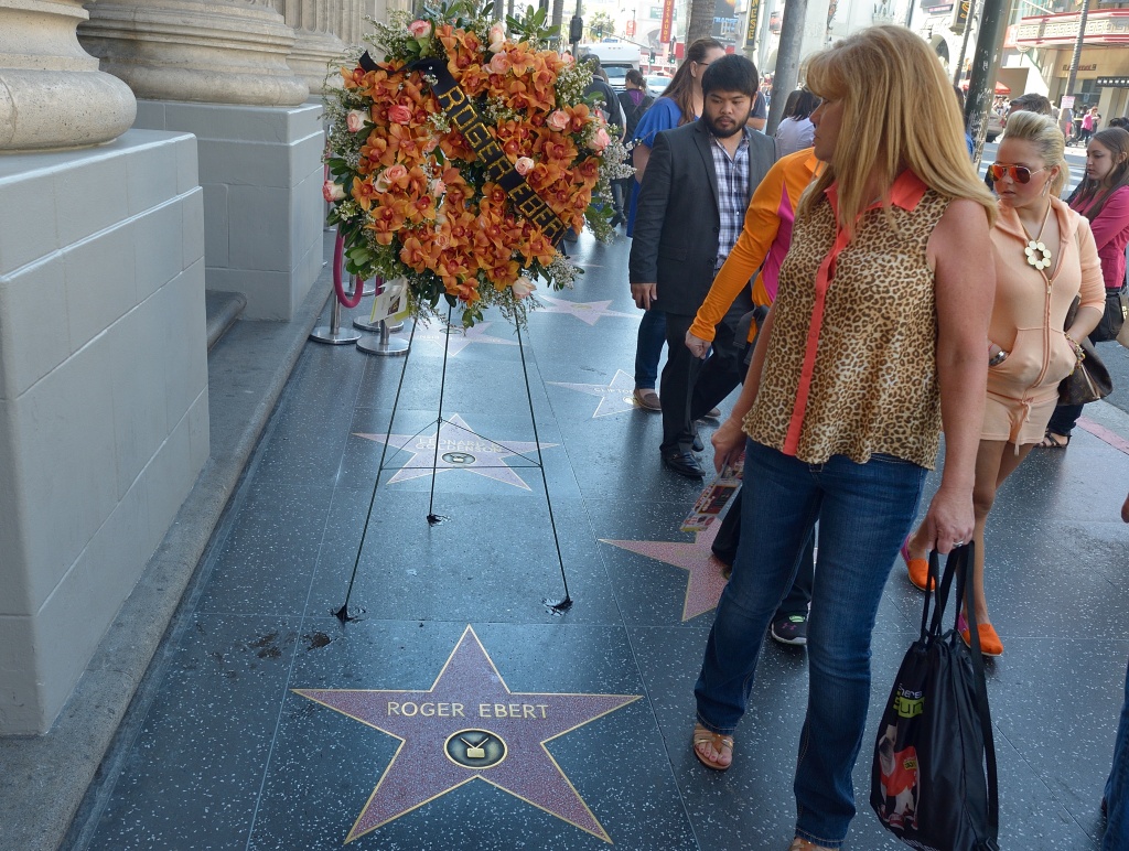 ENTERTAINMENT-US-FILM-MEDIA-EBERT People walk past flowers placed before the Star for Roger Ebert on Hollywood's Walk of Fame April 4, 2013 in Hollywood,California. Ebert, the first film critic to win a Pulitzer Prize, died April 4, 2013, the US newspaper that employed him for more than four decades said. He was 70. Ebert -- who just two days ago announced in a blog post that he was taking a break from his main job -- succumbed to cancer after a long battle, according to the Chicago Sun-Times.