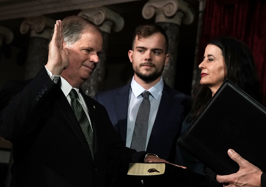 Newly Elected Senators Doug Jones And Tina Smith Sworn Into Senate U.S. Sen. Doug Jones (D-AL) (L) participates in a mock swearing-in ceremony as Jones' wife Louise (R) and son Carson (2nd L) look on at the Old Senate Chamber of the U.S. Capitol January 3, 2018 in Washington, DC.