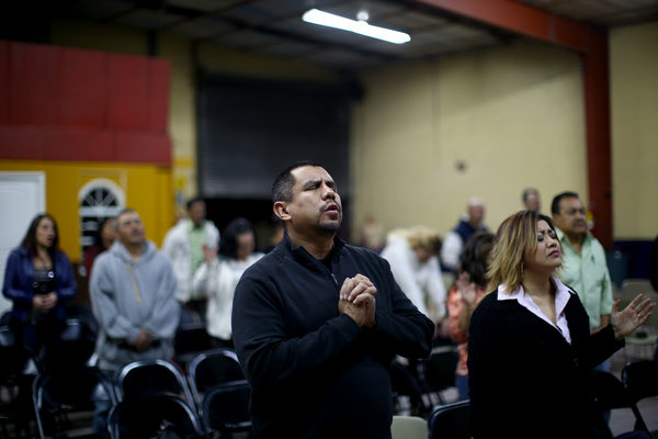 Pastor Robert Salazar (center) prays before giving his sermon at the Pastor Robert Salazar (center) prays before giving his sermon at the
