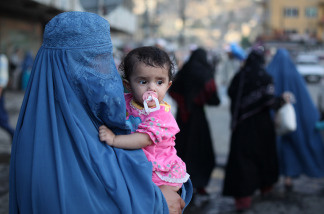 A burqa-clad Afghan woman carries a child through the old town area of Kabul, June 19, 2010. Afghan women worry that peace talks with the Taliban might result in a loss of rights they had slowly regained after the militants' harsh and restrictive rule.