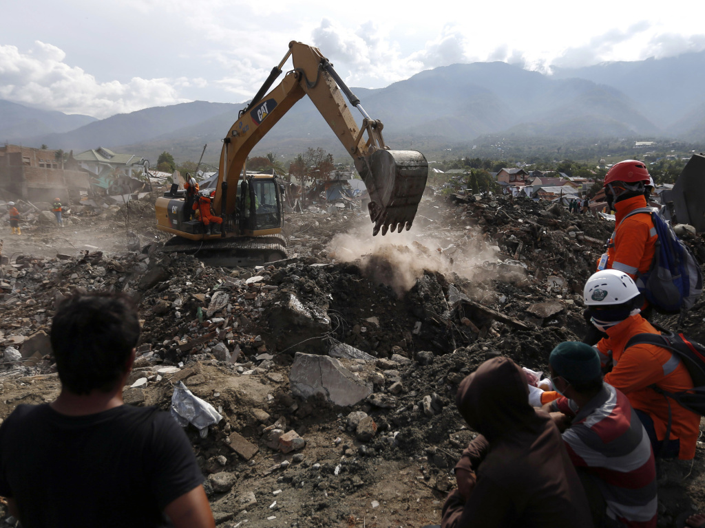 Rescue workers watch as a heavy machine dig through rubble searching for earthquake victims on Thursday in Palu, Central Sulawesi, Indonesia. Rescue workers watch as a heavy machine dig through rubble searching for earthquake victims on Thursday in Palu, Central Sulawesi, Indonesia.