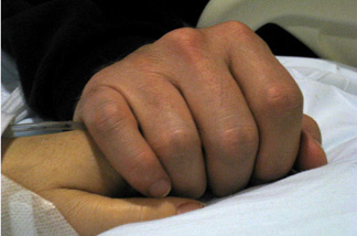 In this handout image provided by U.S. Rep. Gabrielle Giffords' office on Jan. 11, 2011, Mark Kelly, husband of U.S. Rep. Gabrielle Giffords (D-AZ), holds his wife's hand in the congresswoman's hospital room at University Medical Center Jan. 9, 2011 in Tucson, Arizona. Six people were killed and at least 13 others wounded, including Giffords, when a gunman opened fire at a public event held at Tucson Safeway supermarket.