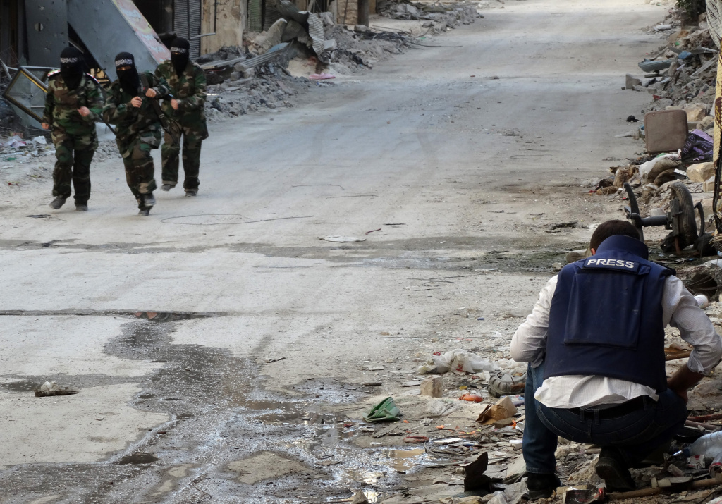 SYRIA-CONFLICT Masked female rebel fighters run past a journalist in the war-wracked Salaheddin district of the northern Syrian city of Aleppo on October 4, 2013. The Syrian regime and its armed opponents have both been accused of carrying out numerous atrocities in the 30-month conflict, which began as a popular uprising and has since snowballed into a full-blown war that has killed 115,000.