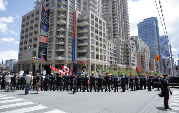 Canadian police forces watch over marchers taking part in the Indigenous Peoples assembly and march through the streets of Toronto two days prior to the opening of the G20 Summit on June 24, 2010 in Toronto, Canada.
