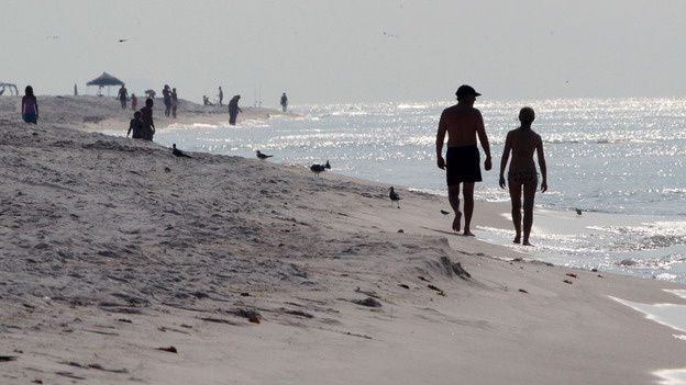 Sunbathers walk along the beach in Pensacola Beach, Fla. on Aug. 1. Local business officials are asking for a substantial federal investment in getting tourists back to the coast after the peak summer season was wiped out by the oil spill.