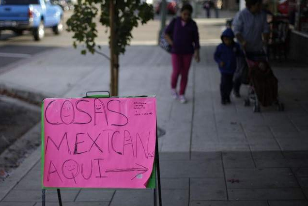 A family passes a sign that reads, 'Mexican things here,' in Escondido.