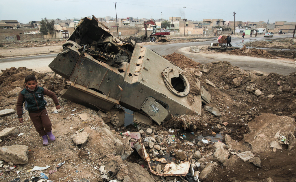 TOPSHOT-IRAQ-CONFLICT-MOSUL An Iraqi boy walks past a destroyed armored vehicle near the University of Mosul after government forces retook control of the area from ISIS during the ongoing military operation against the jihadists on January 21, 2017.