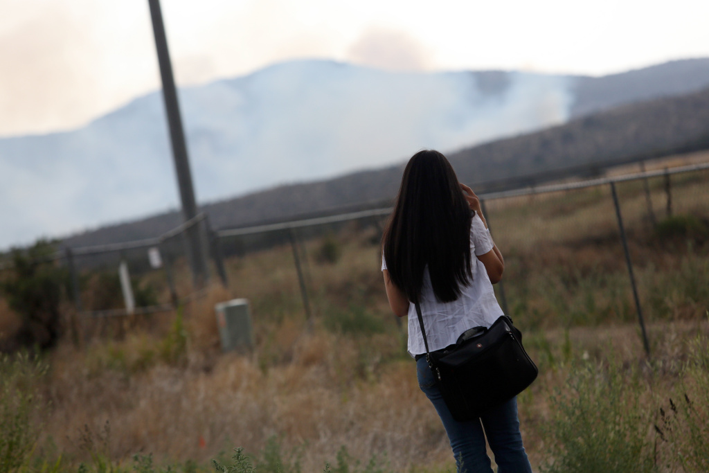 US-ARIZONA-FIRE-TOLL A woman looks at smoke from the Yarnell fire near a roadblock on the road to Yarnell, Arizona, on July 1, 2013. Reinforcements poured in Monday to battle a runaway wildfire which quadrupled in size overnight after killing 19 firefighters in one of the worst such incidents in US history. The Yarnell Hill fire -- which killed all but one member of a 20-strong 'hotshot' team -- was the biggest loss of firefighters' lives since the September 11 attacks, and the most from a US wildfire in 80 years.