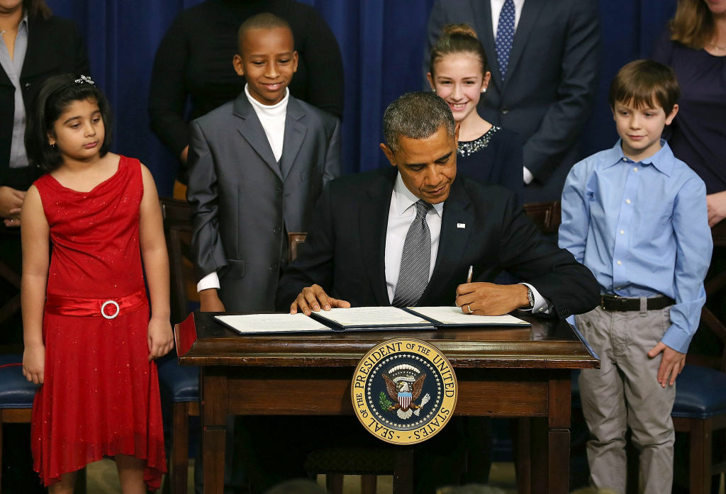 Obama And Biden Unveil Proposal To Decrease Gun Violence In U.S. U.S. President Barack Obama signs a series of executive orders about the administration's new gun law proposals as children who wrote letters to the White House about gun violence, (L-R) Hinna Zeejah, Taejah Goode, Julia Stokes and Grant Fritz, look on in the Eisenhower Executive Office building, on January 16, 2012 in Washington, DC. One month after a massacre that left 20 school children and 6 adults dead in Newtown, Connecticut, the president unveiled a package of gun control proposals that include universal background checks and bans on assault weapons and high-capacity magazines.