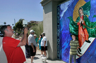 San Diego resident Brennan Savage photographs his son, Liam, posing with the Madonna-surfing mosaic on Encinitas Boulevard's railroad bridge support.