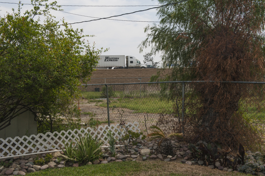 Warehouse Emissions Trucks on the SR 60 Freeway are seen from Anna Gallegos' backyard in Mira Loma Village, California