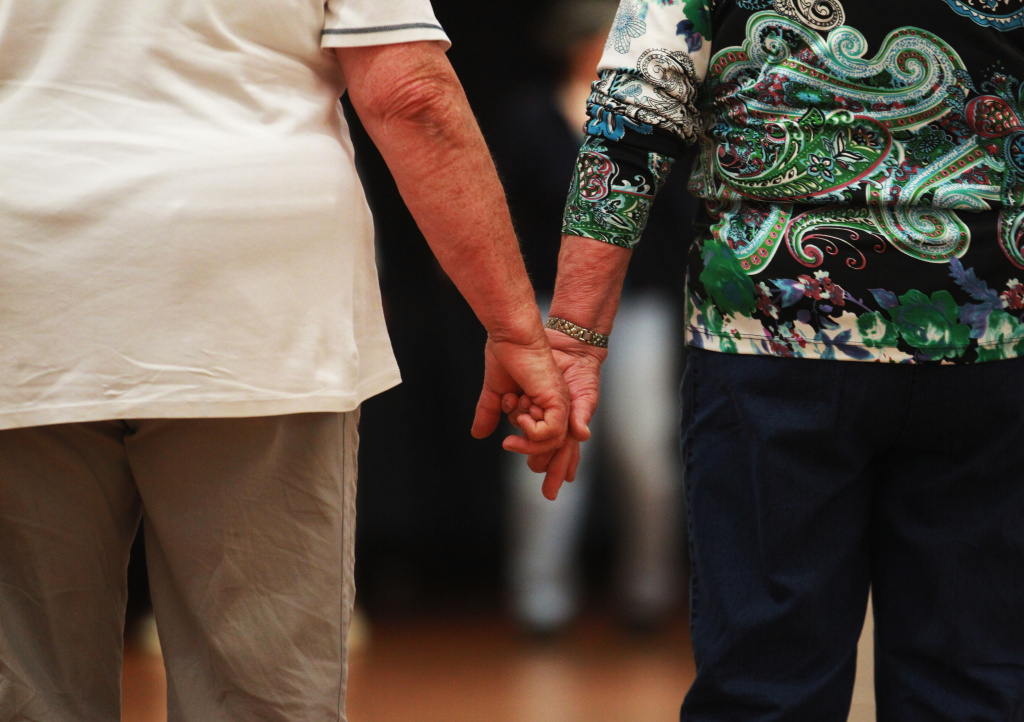 An elderly couple hold hands at a trade fair at the “Seniorentag 2012” senior citizens convention on May 3, 2012 in Hamburg, Germany. The three-day long convention caters specifically to the needs of elderly people, who in Germany, as in the rest of Europe, are becoming an increasingly higher portion of the overall population. Europe as a whole, through its low birth rates and improving health care, is undergoing a demographic shift that has far-reaching consequences for labor markets, public policy planning and government budgets.