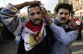 An Egyptian anti-regime protester wounded during clashes with government supporters is escorted by a fellow demonstrator to get medical treatment at a makeshift clinic at the Ibad al-Rahman mosque near the flashpoint Tahrir square in Cairo on Feb. 2, 2011.