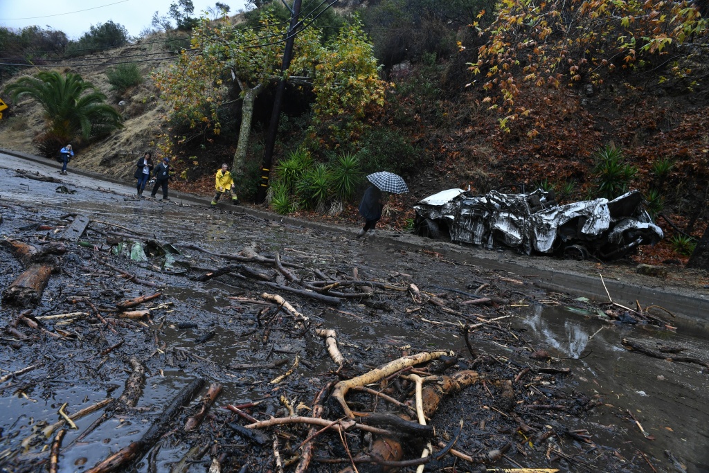US-WEATHER-MUDSLIDES A firefighter (in yellow) instructs journalists to retreat to safer ground after a rain-driven mudslide destroyed two cars and damaged property in a neighborhood under mandatory evacuation in Burbank, California, January 9, 2018.
Mudslides unleashed by a ferocious storm demolished homes in southern California, authorities said Tuesday. Five people were reported killed. / AFP PHOTO / Robyn Beck (Photo credit should read ROBYN BECK/AFP/Getty Images)