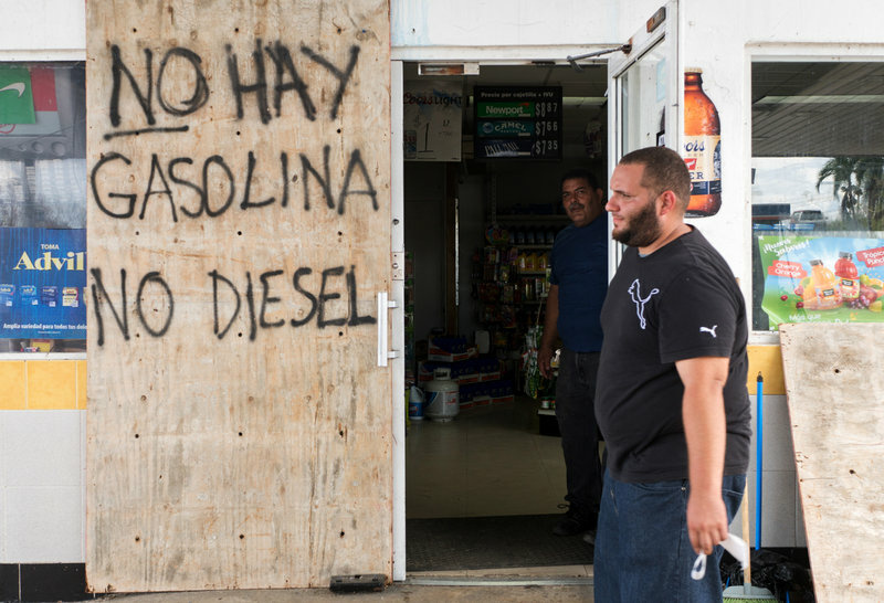 Puerto Rico Hurricane Manager Carlos de Armas walks by the entrance to the Gulf Route 65 gas station as people wait for a tanker truck to arrive.
