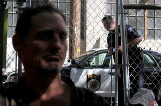 Mercer 20035 A Sacramento police officer looks in at a homeless man at a 'Safe Ground' encampment August 26, 2009 in Sacramento, California.