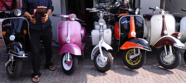 Mercer 17761 A shop owner stands next to old models of refurbished Vespa scooters.