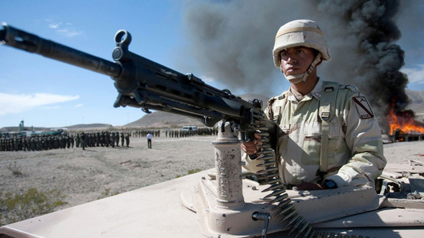 A Mexican soldier stands guard as a haul of marijuana and cocaine are incinerated in the background in November 2009.
