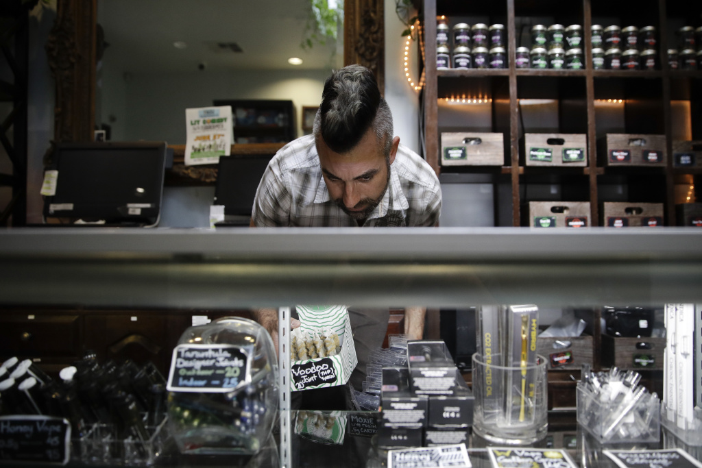 Marijuana Cash Business In this June 27, 2017, photo, Jerred Kiloh, owner of the Higher Path medical marijuana dispensary, stocks shelves with with cannabis products in Los Angeles. On a typical day, $15,000 can change hands in his dispensary, where a steady stream of customers pick from shelves stocked with hundreds products, from cannabis-infused lip balm to potent concentrates that look like thin sheets of amber-colored ice.