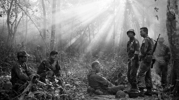 The sun breaks through dense jungle foliage as South Vietnamese troops, joined by U.S. advisers, rest after a cold, damp and tense night of waiting in an ambush position for a Viet Cong attack that didn't come, January 1965.