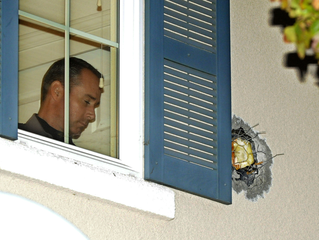 A Dublin Police officer stands near the exit hole of a cannonball in the second story wall after it traveled through the California home on Tuesday. The cannonball was misfired during the taping of an episode of the Discovery Channel show "MythBusters" at the Alameda County Bomb Disposal Range.
