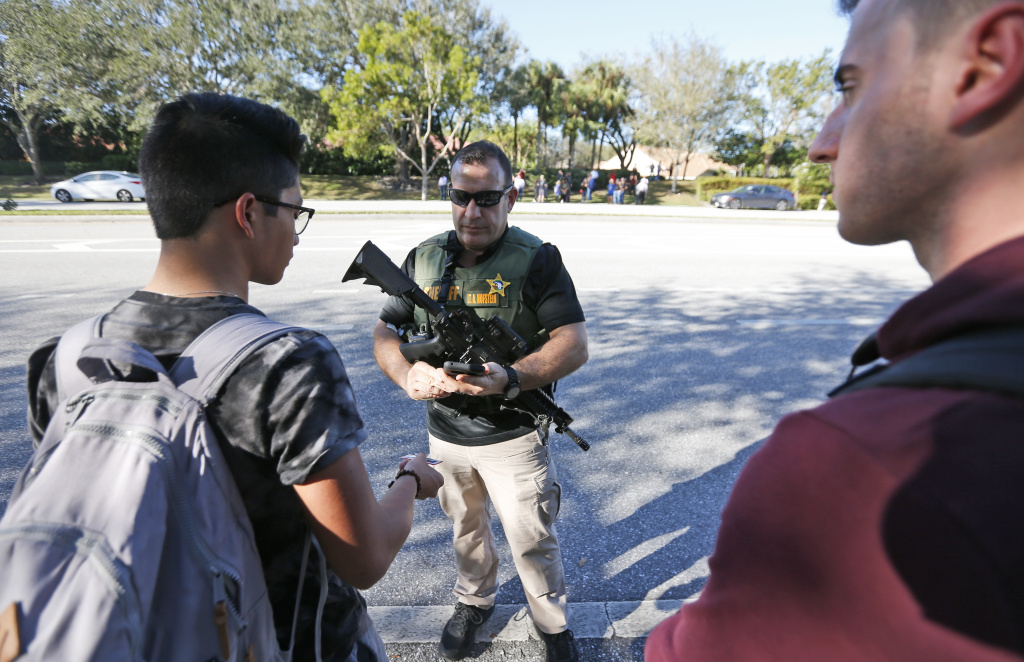 School Shooting Florida A law enforcement officer talks with students, Wednesday, Feb. 14, 2018, in Parkland, Fla. A shooting at Marjory Stoneman Douglas High School sent students rushing into the streets as SWAT team members swarmed in and locked down the building. Police were warning that the shooter was still at large even as ambulances converged on the scene and emergency workers appeared to be treating those possibly wounded.