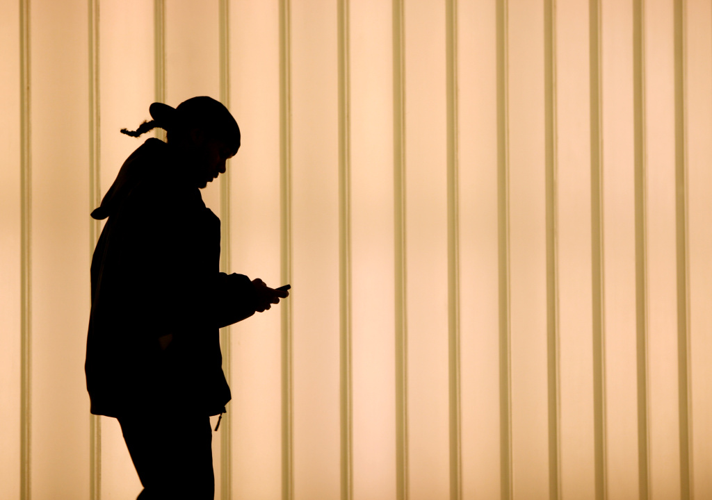 A woman walks inside of the World Tradin A woman walks while using a cell phone in New York.