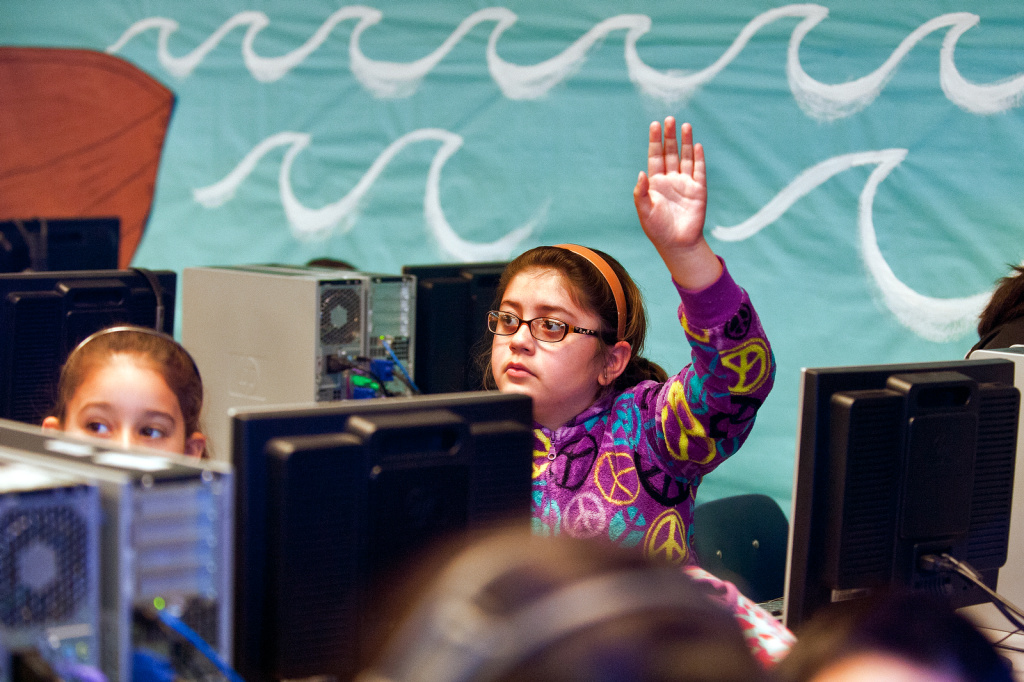 Dual Language API - 8 Third grader Natalia Gonzalez raises her hand as students take quizzes during a computer lab session.