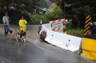 Residents walk past barriers setup to divert floodwaters as heavy rain raises the possibility of flooding and landslides due to the denuded hillside vegetation from the recent Station Fire in the La Canada Flintridge area of Los Angeles. File photo.