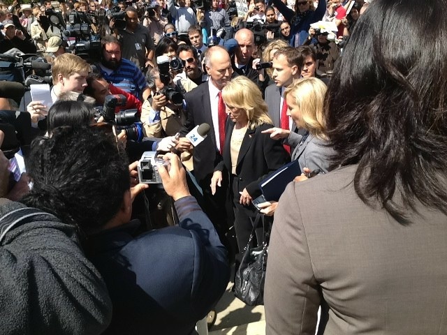 Media and protesters swarm Arizona Governor Jan Brewer as she exits U.S. Supreme Court.