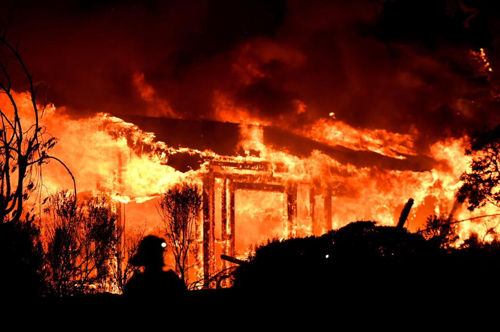 TOPSHOT-US-WILDFIRES-CALIFORNIA Firefighters assess the scene as a house burns in Napa, California on October 9, 2017.