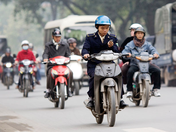 Motorcycles are the primary form of transportation in Vietnam, and public health officials are raising the alarm about a new road hazard: texting while driving. Here, a man checks his cell phone while driving in downtown Hanoi, Vietnam, in January.