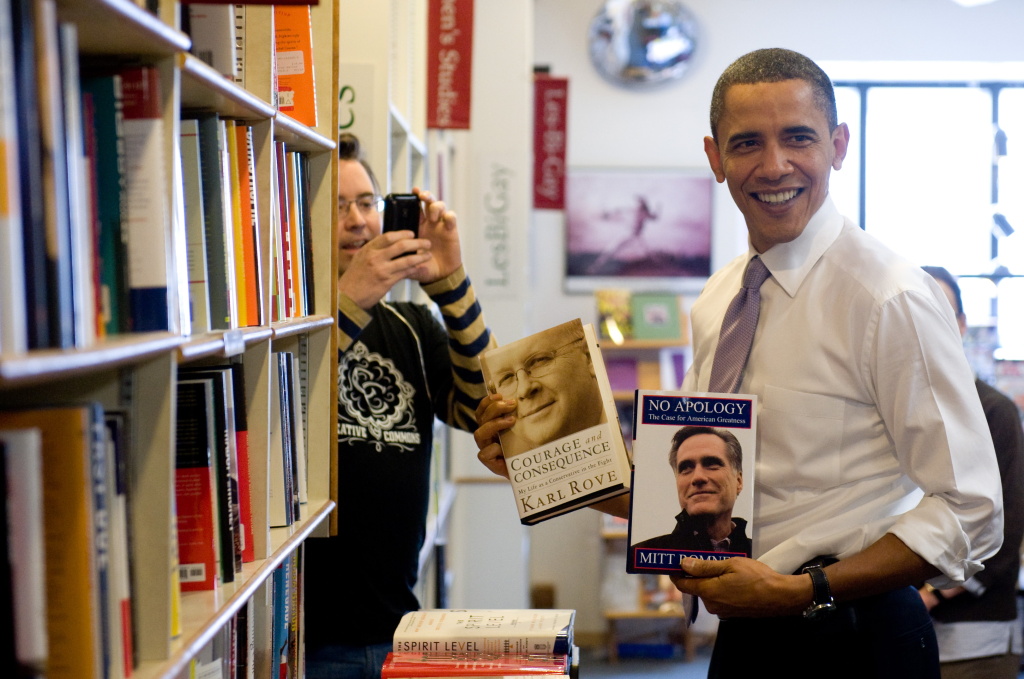 US President Barack Obama holds up copie US President Barack Obama holds up copies of Karl Rove's book and Mitt Romney's book at the Prairie Lights Bookstore during an unscheduled stop in Iowa City, Iowa, March 25, 2010.