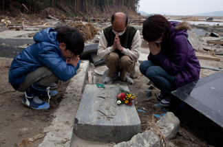 A month after the tsunami divastation, a family prays by a grave in Ishinomaki, Miyagi prefecture on April 11, 2011.