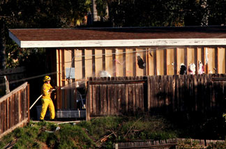 Fire department officials spray retardant on a structure next to the home of George Jura Jakubec before it was set ablaze by officials December 9, 2010 in Escondido, California.