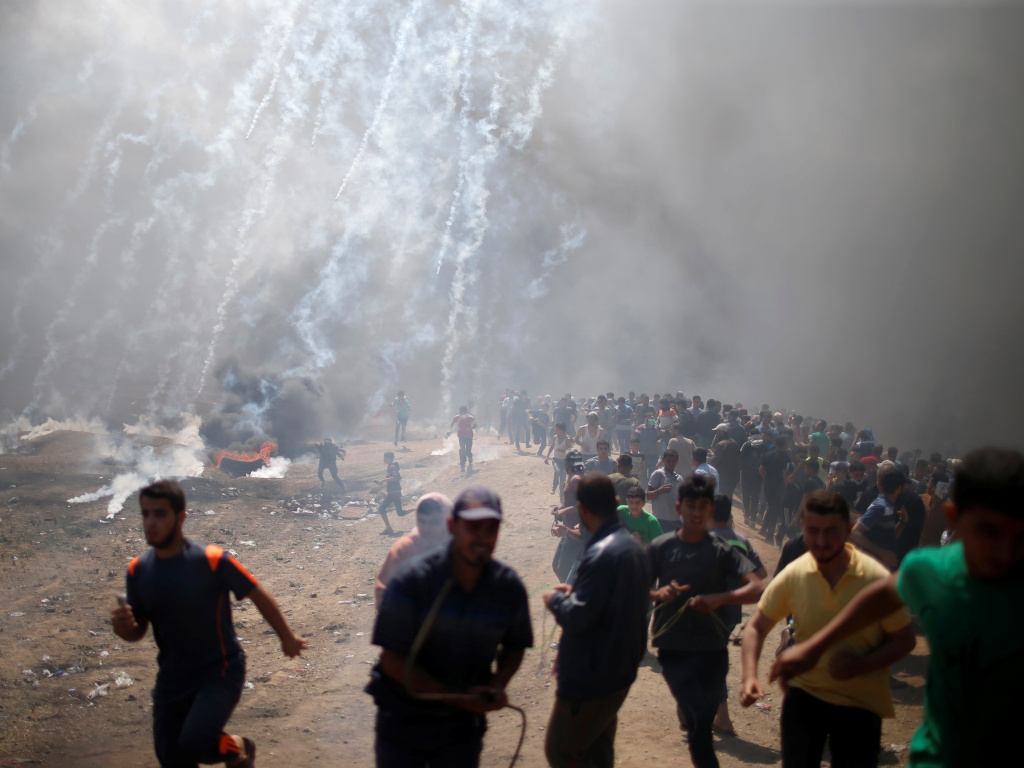 Palestinian demonstrators run from tear gas fired by Israeli troops during a protest against the U.S. embassy move to Jerusalem and ahead of the 70th anniversary of Nakba, at the Israel-Gaza border east of Gaza City. Palestinian demonstrators run from tear gas fired by Israeli troops during a protest against the U.S. embassy move to Jerusalem and ahead of the 70th anniversary of Nakba, at the Israel-Gaza border east of Gaza City.