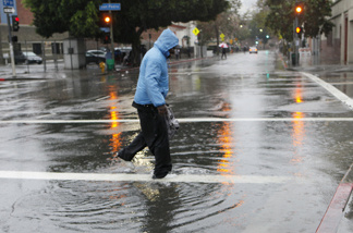 A pedestrian walks through a flooded gutter in Los Angeles, Monday, Dec. 20, 2010.
