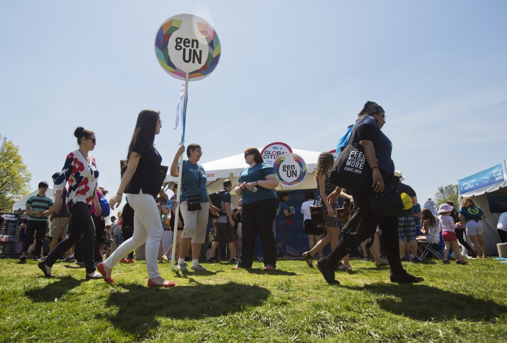 US-FESTIVAL-ENVIRONMENT -EARTH DAY Concert attendees walk past information stands during the 2015 Earth Day concert in Washington, DC on April 18, 2015.