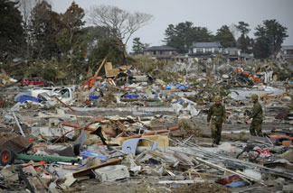 Japanese self defense personnel walk amongst a tsunami devastated town, close to the airport in Sendai on March 14, 2011.