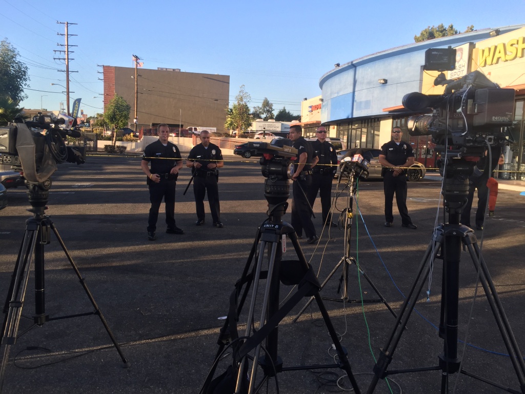 South Los Angeles OIS Police stand behind caution tape at the scene of an officer-involved shooting that left an 18-year-old man dead. Officers say he produced a hand gun after leading them on a car chase.