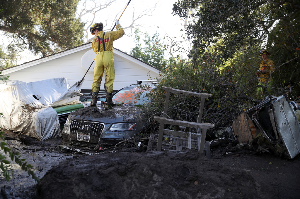 Mudslides Kill At Least 17 People In Santa Barbara County Where Wildfire Scorched Hillside A Cal Fire firefighter looks through a car next to a home that was destroyed by a mudslide on January 12, 2018 in Montecito, California.
