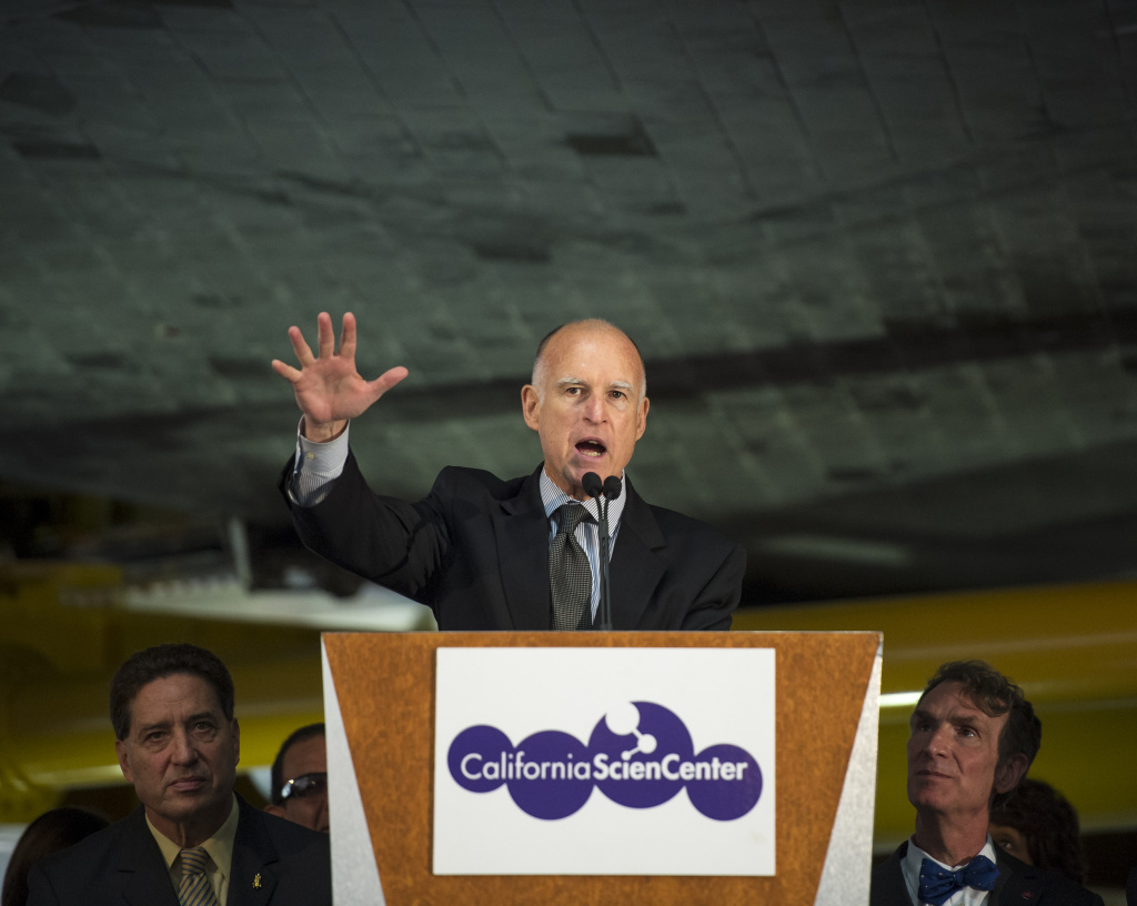California Governor Jerry Brown speaks from a podium underneath the space shuttle Endeavour during the grand opening ceremony for the California Science center's Samuel Oschin Space Shuttle Endeavour Display Pavilion, on October 30, 2012, in Los Angeles, California.
