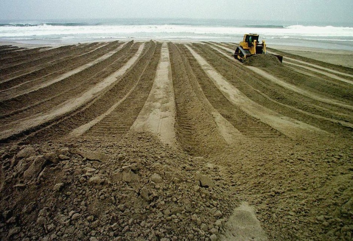 1938: People walk along the flooded L.A. River near the Dayton Avenue Bridge. In the background, a railroad bridge hangs in a twisted heap after one of the pilings has collapsed. (Photograph courtesy of the Los Angeles Public Library)