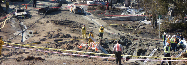 Accident scene with the crater in the foreground and the ruptured pipe section in the background