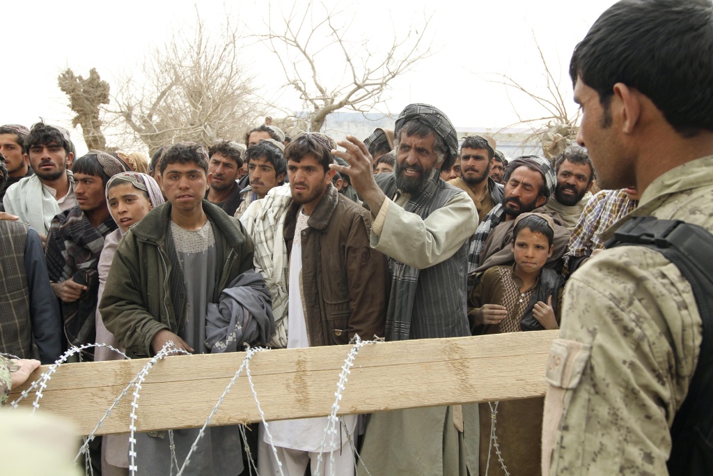 An Afghan soldier speaks to civilians gathered outside a military base in Panjwai, Kandahar province south of Kabul, Afghanistan, Sunday, March 11, 2012. Afghan President Hamid Karzai says a U.S. service member has killed more than a dozen people in a shooting including nine children and three women. An Afghan soldier speaks to civilians gathered outside a military base in Panjwai, Kandahar province south of Kabul, Afghanistan, Sunday, March 11, 2012. Afghan President Hamid Karzai says a U.S. service member has killed more than a dozen people in a shooting including nine children and three women.