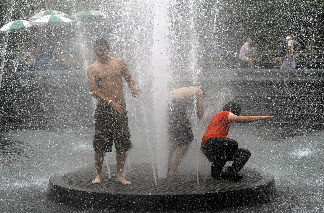 Three boys stand in the middle of the fountain in Washington Square Park in New York July 8, 2010 as high temperatures and humidity continue on the east coast.
