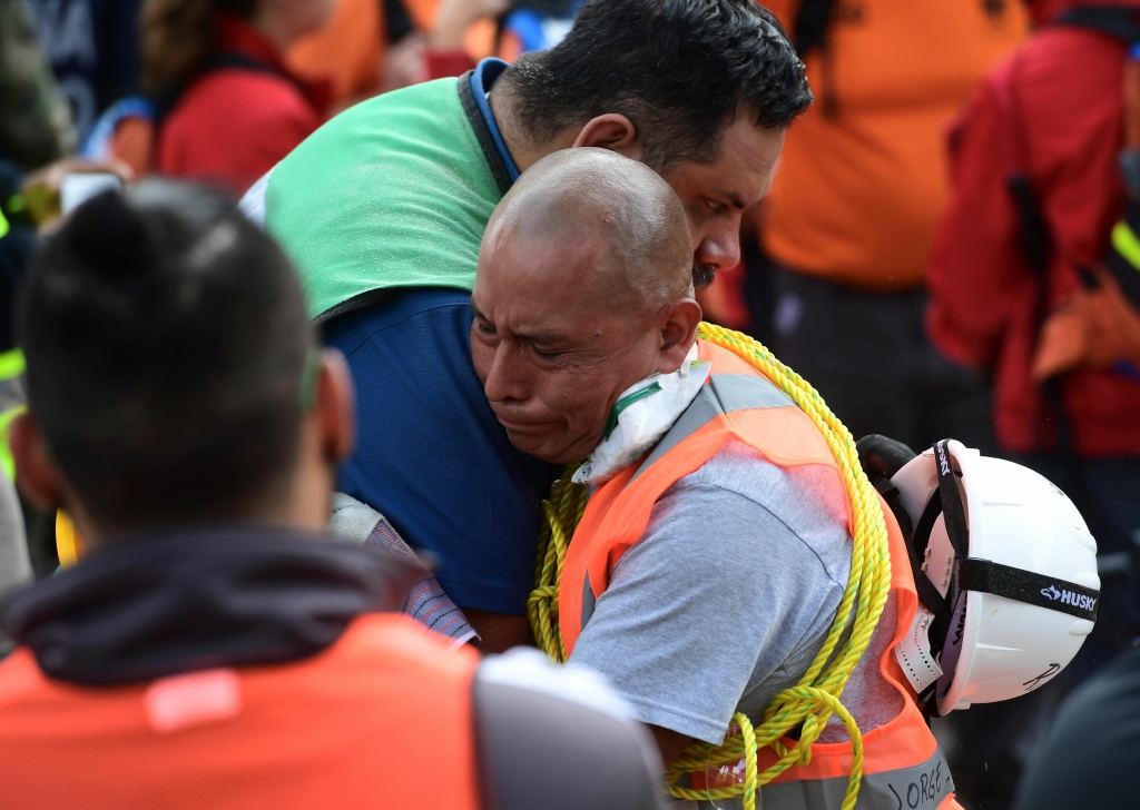 MEXICO-QUAKE Rescue workers embrace each other deeply moved after a seismic alert sounded in Mexico City on September 23, 2017, four days after the powerful quake that hit central Mexico.
In the capital, the quake toppled 39 buildings, mostly in a central area with older construction that is popular with tourists and foreigners living in the city, and also in the south. / AFP PHOTO / RONALDO SCHEMIDT (Photo credit should read RONALDO SCHEMIDT/AFP/Getty Images)